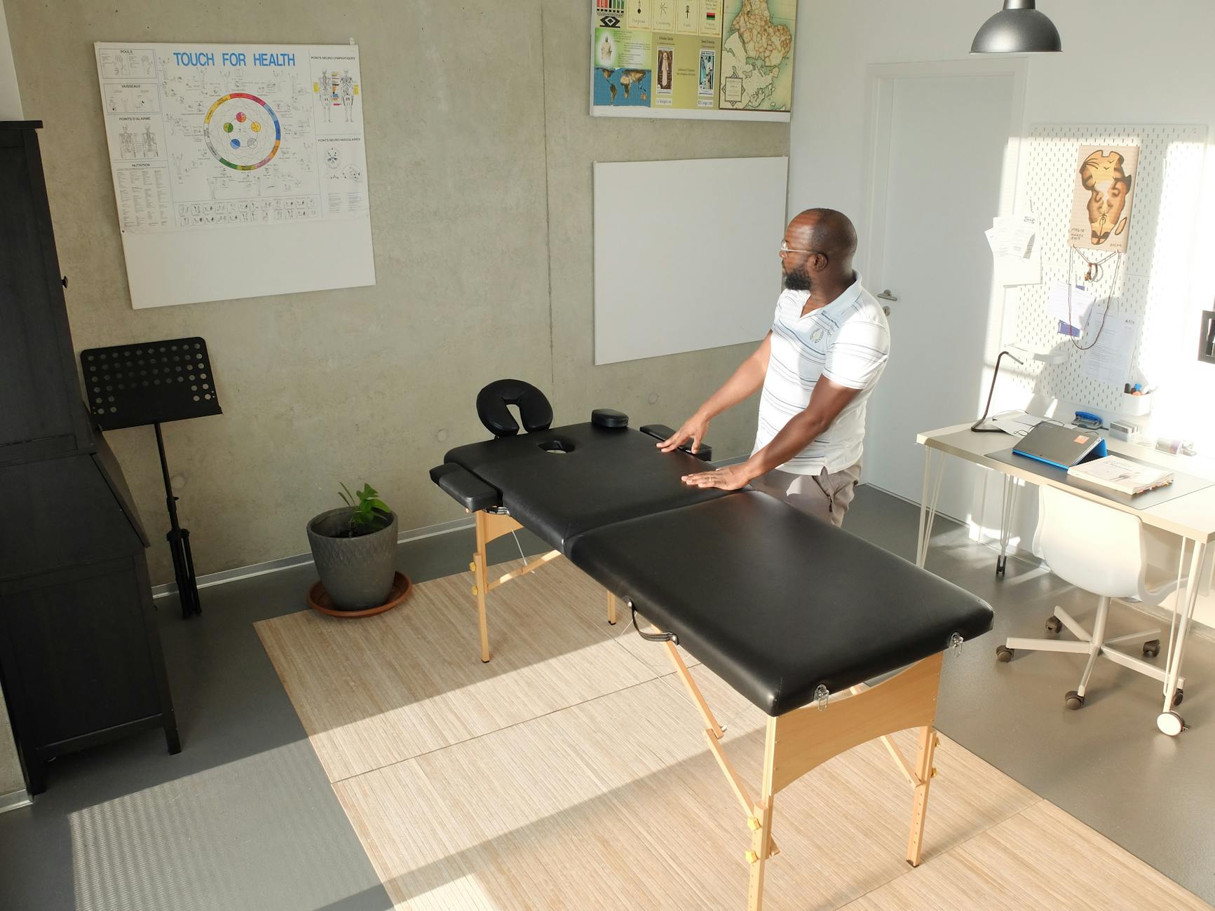 Fizjoterapeuta przy stole do masażu w jasnym gabinecie