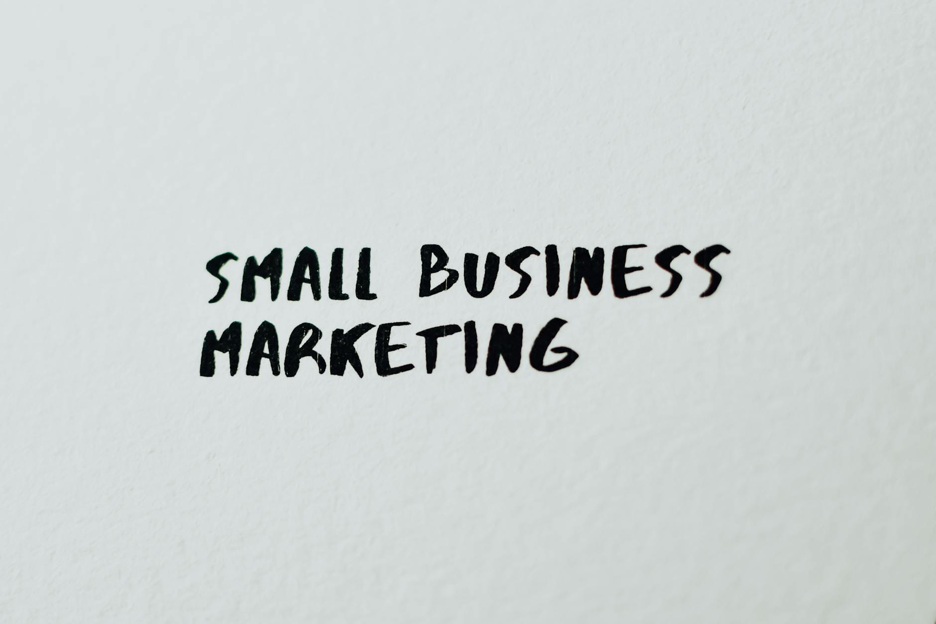 Jak wykorzystać sztuczną inteligencję do automatyzacji marketingu w małej firmie Napis Small Business Marketing na białej kartce papieru