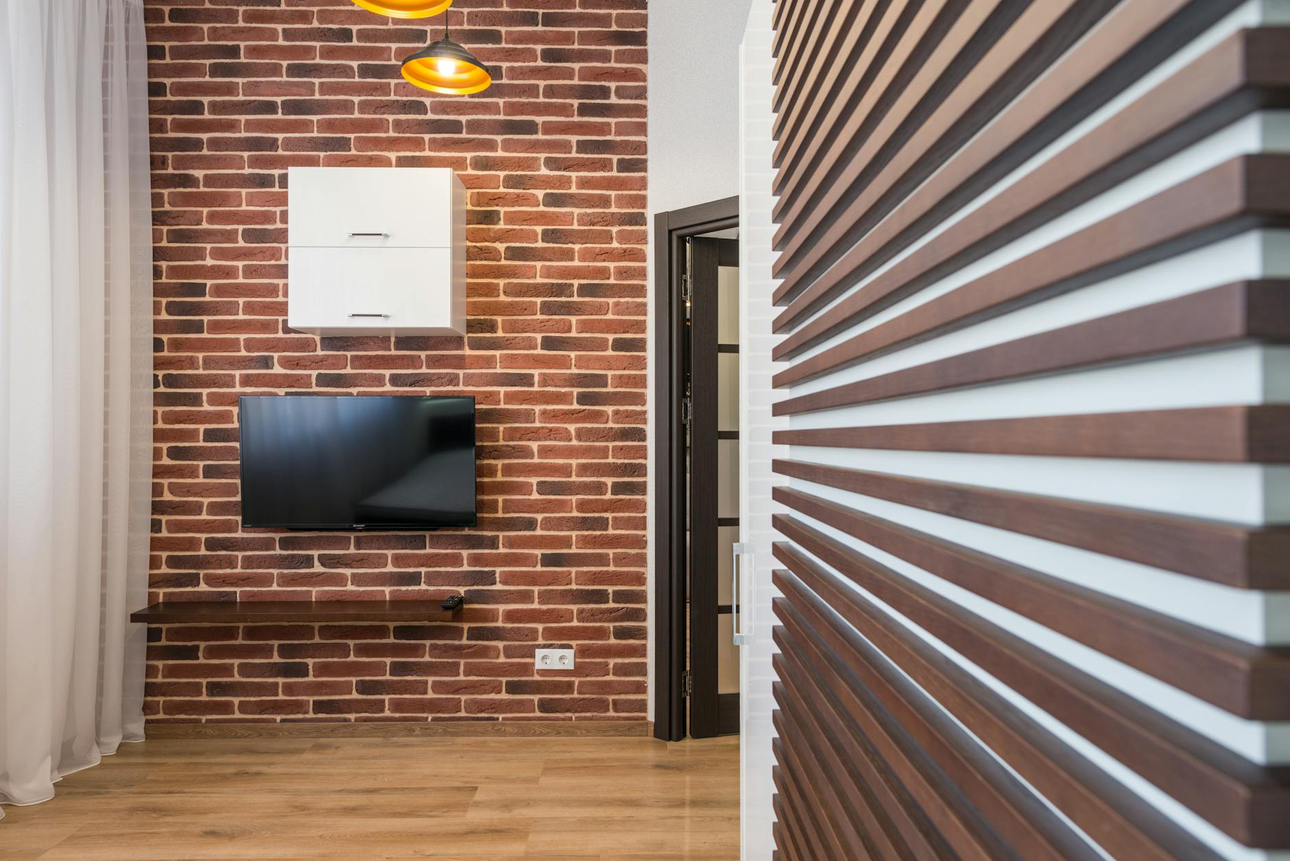 Nowoczesny salon z ceglą ścianą, telewizorem i drewnianymi akcentami