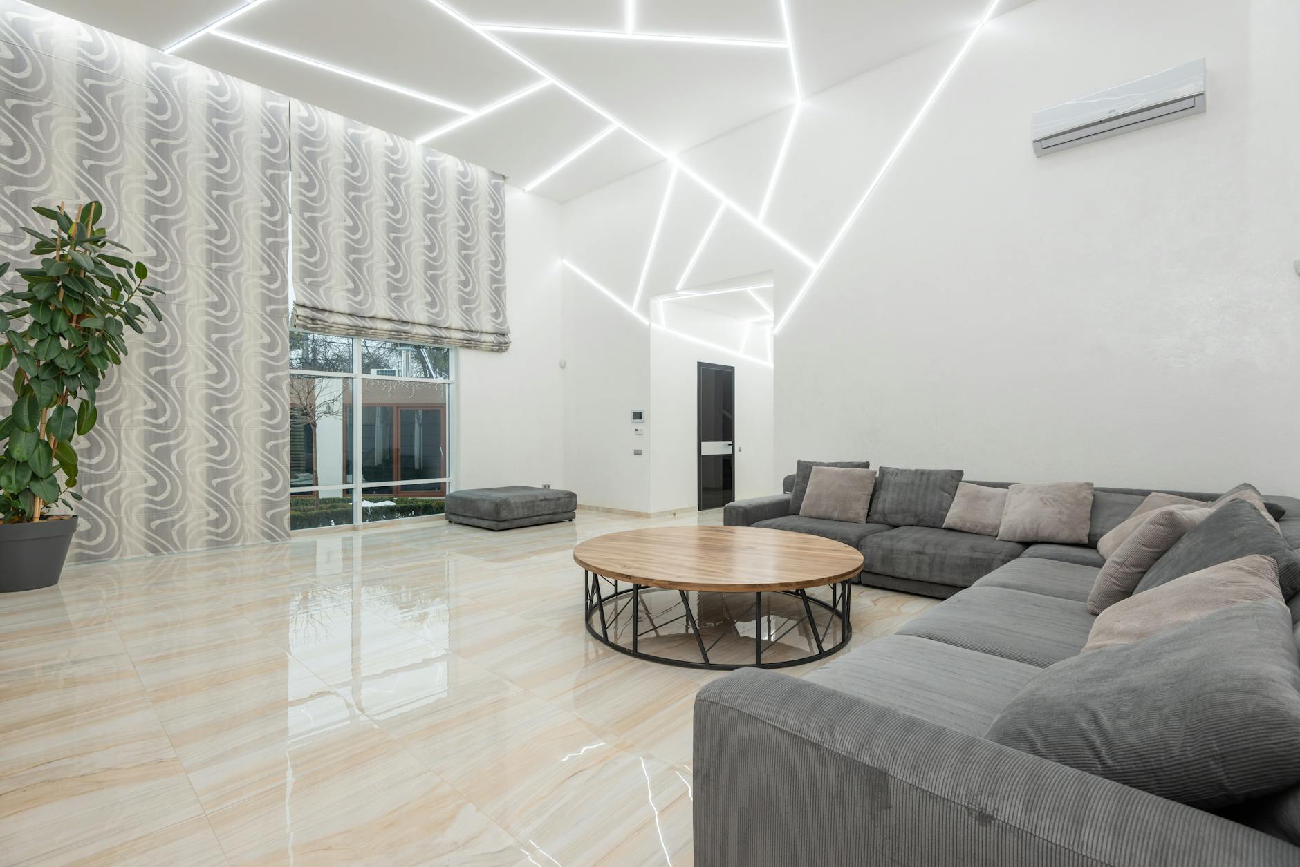 Nowoczesny salon z narożną sofą i dużymi oknami w jasnym wnętrzu