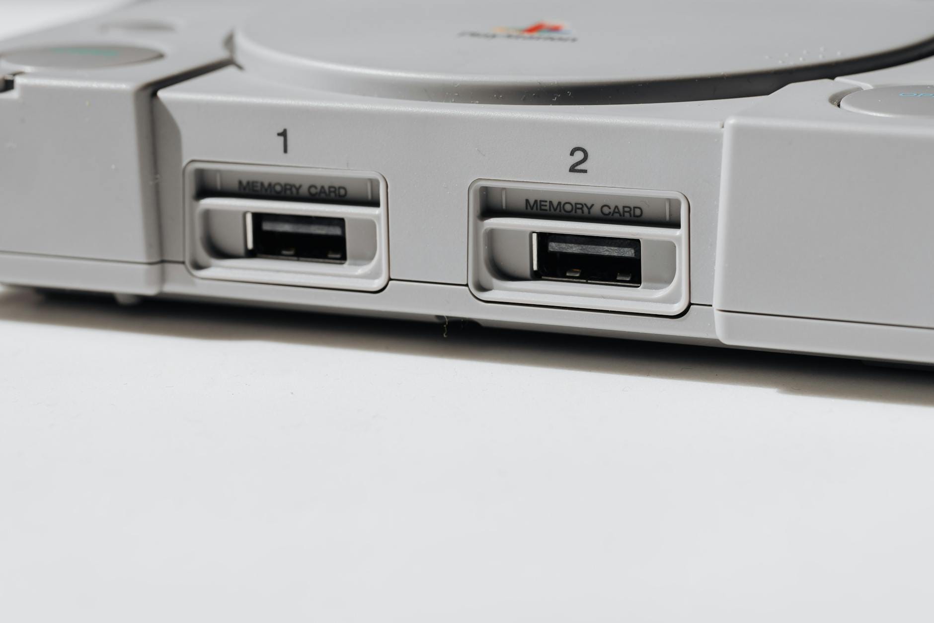 Zbliżenie na retro konsolę PlayStation z widocznymi slotami na karty pamięci