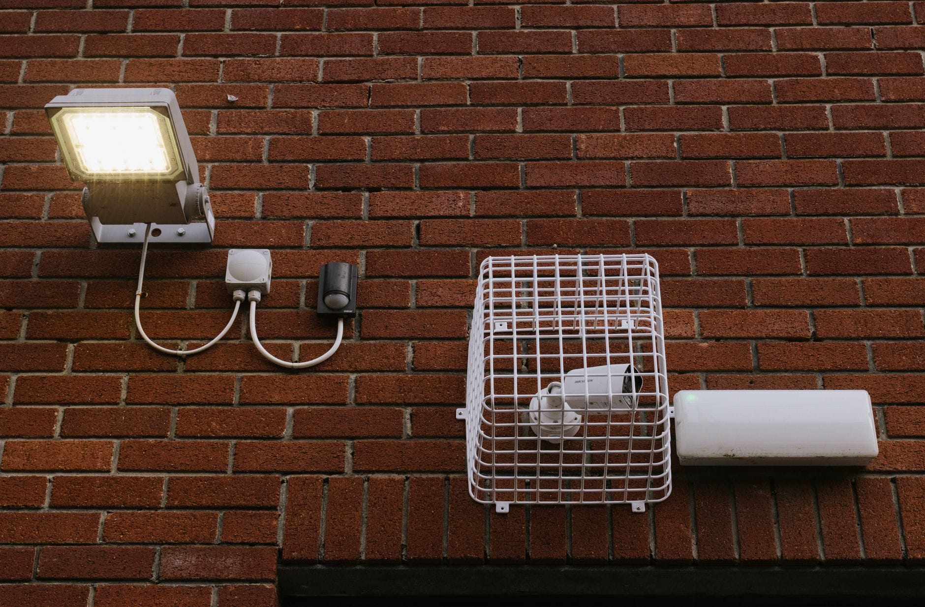Oświetlenie włączane czujnikiem ruchu w korytarzu: kiedy ma sens, gdzie je montować i jakie lampy wybrać do mieszkania Ściana z cegły z lampą LED i kamerą z czujnikiem ruchu